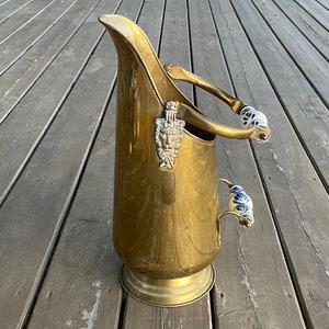 May include: A gold metal coal scuttle with a decorative handle and two porcelain handles with blue and white floral designs.