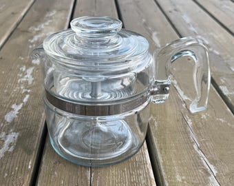 Può includere: Una caffettiera in vetro trasparente con coperchio in vetro abbinato, un robusto manico in vetro e una fascia metallica centrale. Il corpo in vetro presenta tacche di misurazione per 2 e 4 tazze, con un perno metallico interno centrale.