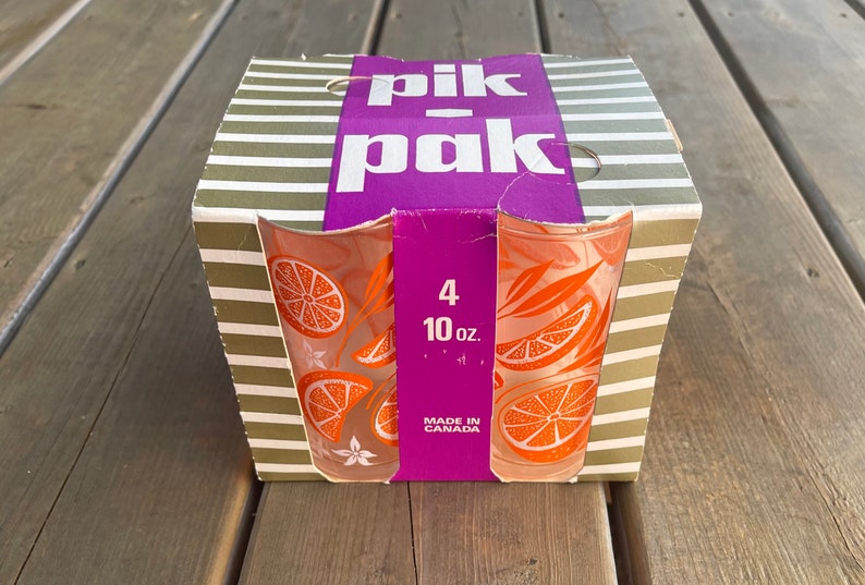 May include: A box of four 10-ounce orange juice glasses with a citrus design. The box is green and white striped with a purple label that says "pik-pak" and "Made in Canada".