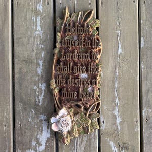May include: A rectangular, brown decorative plaque with the text "Delight thyself in the Lord and He shall give thee the desires of thine heart." The plaque is adorned with floral and leaf accents and a rose.