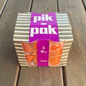 May include: A set of four 10-ounce glass tumblers with an orange slice design. The box is purple and white with the text "pik-pak" and "Made in Canada".