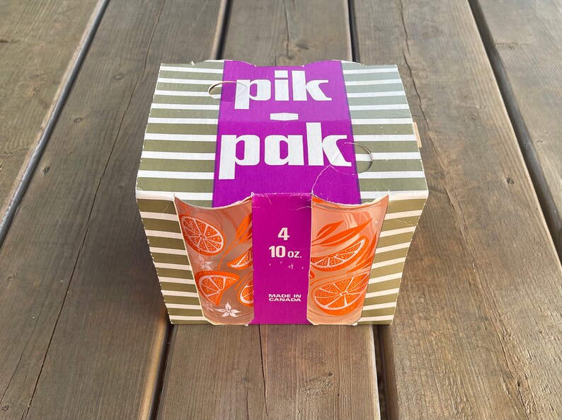 May include: A set of four 10-ounce glass tumblers with an orange slice design. The box is purple and white with the text "pik-pak" and "Made in Canada".
