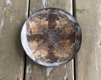 Op de afbeelding: Een ronde decoratieve schaal met een glanzende harsafwerking over een centrale rangschikking van bruine vlindervleugels. De vleugels zijn in een symmetrisch kruispatroon geplaatst met zichtbare licht- en donkerbruine markeringen onder een laag.