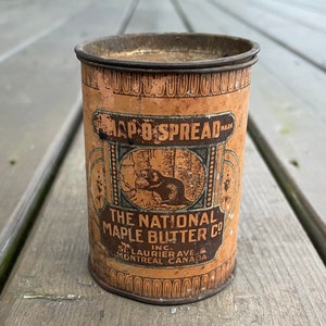 May include: A vintage tin can for Map-O-Spread maple butter. The can is brown with a beaver illustration and the text "The National Maple Butter Co. Inc. St. Laurier Ave. Montreal Canada" printed on it.