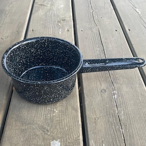 May include: A black enamel saucepan with a speckled finish and a long handle.