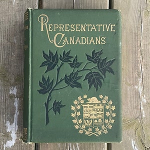 May include: A green book with the title "REPRESENTATIVE CANADIANS" in gold lettering. The cover features a stylized maple leaf branch and the Canadian coat of arms.