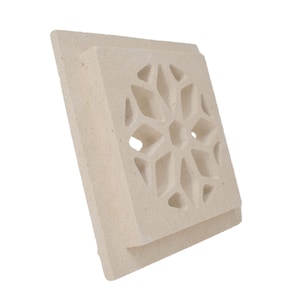 Può includere: Una griglia di ventilazione decorativa quadrata bianca con un design geometrico scolpito. Il design ricorda un fiocco di neve o una stella.