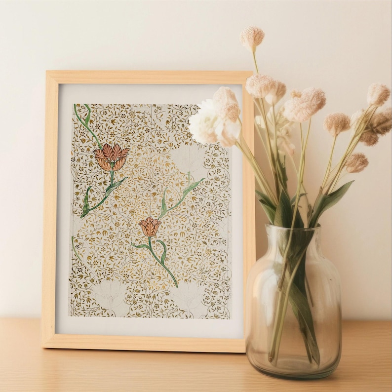 May include: A framed print featuring a repeating pattern of gold foliage and two prominent orange tulips on a light background, positioned next to a clear glass vase containing several dried, light-colored, round-headed flowers.