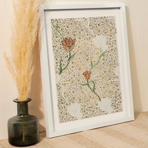 May include: A framed print featuring a dense, intricate pattern of gold and brown foliage and vines on a light background, accented by two prominent orange tulips with green stems and leaves, enclosed in a simple white rectangular frame.