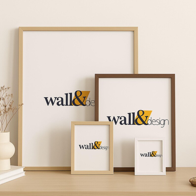 May include: Four rectangular picture frames of varying sizes and colors, including light wood, medium brown, and white finishes. Each frame contains a white insert featuring the dark blue and yellow text wall&design centered on the surface.