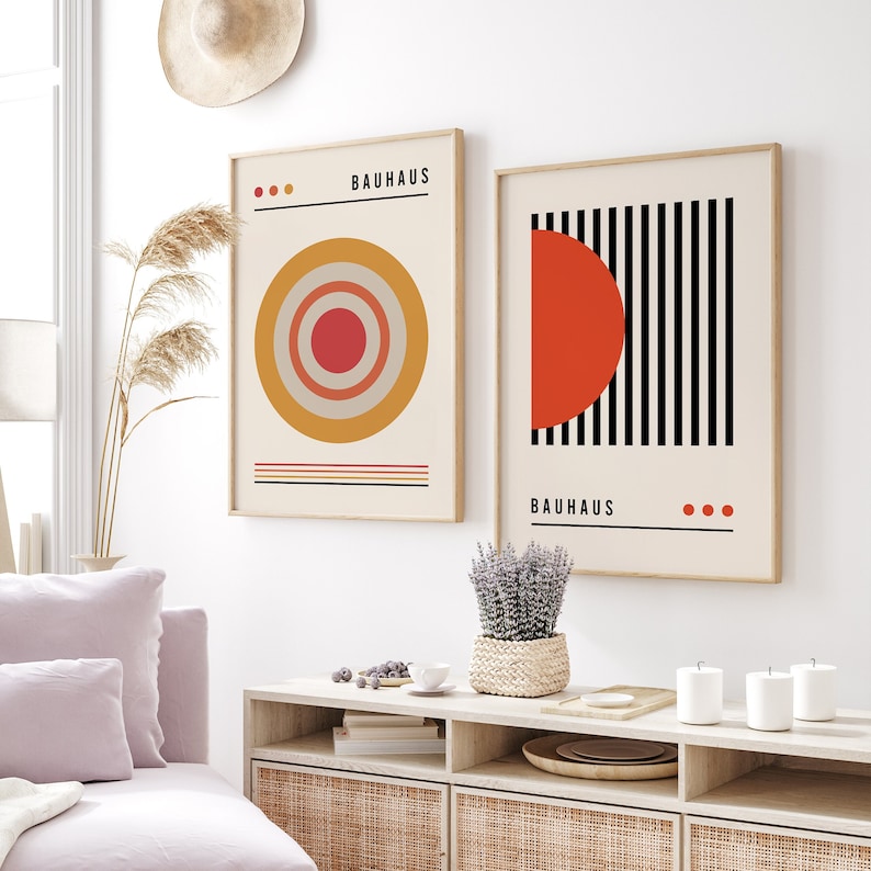 May include: Two framed wall art prints featuring Bauhaus designs. The left print displays concentric circles in red, orange, and beige with the text Bauhaus. The right print shows a red semicircle against vertical black stripes with the text Bauhaus.