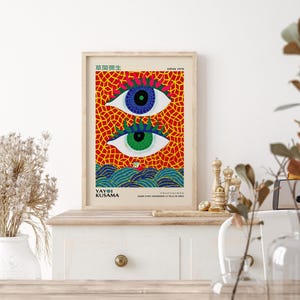 Framed art print featuring two stylized eyes with blue and green irises, set against a red mosaic background.