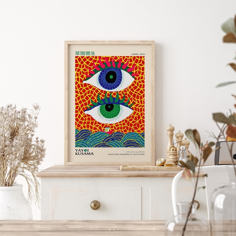 Framed art print featuring two stylized eyes with blue and green irises, set against a red mosaic background.