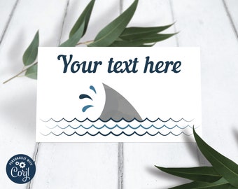 May include: Editable food tent card with a shark fin and waves in blue and gray. The text "Your text here" is at the top of the card.