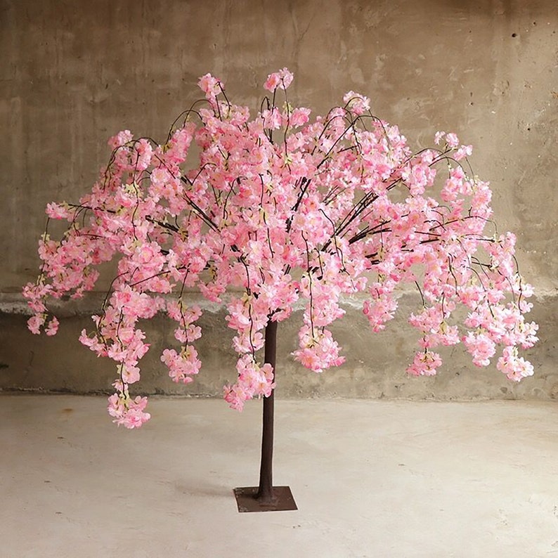 Puede incluir: Un &aacute;rbol artificial de cerezo en flor rosa con un tronco y ramas negras. El &aacute;rbol est&aacute; en plena floraci&oacute;n y las flores caen en cascada.