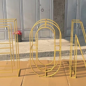 May include: Four gold metal letters spelling out the word "EON" standing on a brown surface. Each letter is made of a series of connected metal bars.
