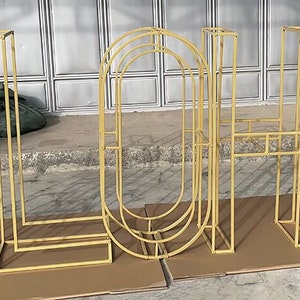 May include: Gold metal letters spelling out the word "ALOHA" in a modern, geometric style. The letters are freestanding and appear to be made of thin metal rods.