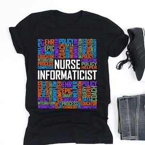 May include: Black t-shirt with the words "NURSE INFORMATICIST" in white, surrounded by colorful words like "POLICY", "COMPUTER", and "WORKFLOW". The shirt is paired with black sneakers, blue jeans, and white wireless earbuds.