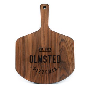 A wooden pizza board with the text "OLMSTED PIZZERIA" engraved on it.