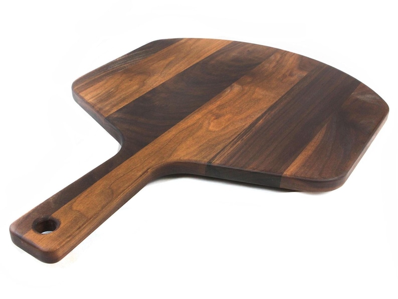 A wooden pizza board with a dark brown finish and a lighter brown handle.
