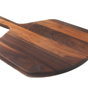 A wooden pizza board with a dark brown, natural wood grain pattern.