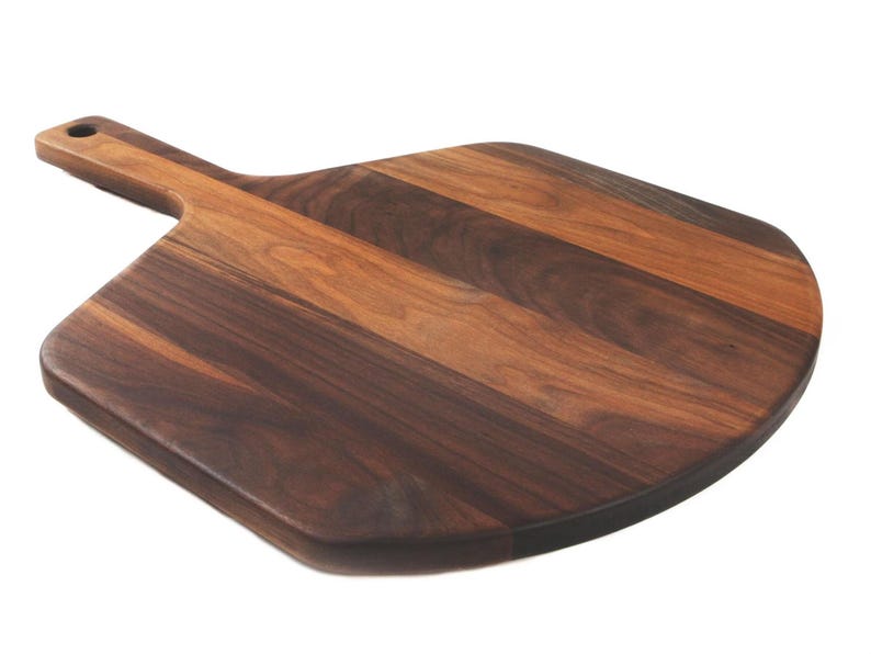 A wooden pizza board with a dark brown, natural wood grain pattern.