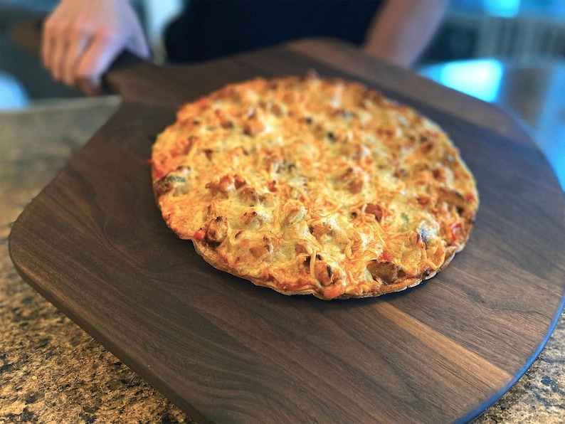 A freshly baked pizza with a golden crust and melted cheese sits on a wooden serving board.