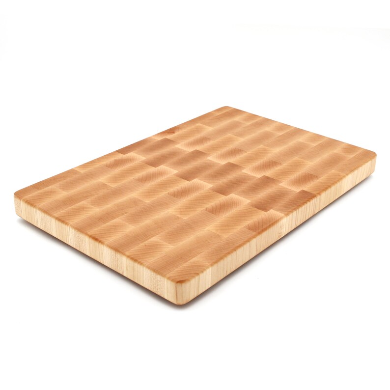 A wooden cutting board with a light-colored, natural wood grain texture.