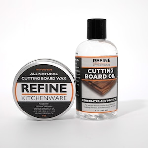 May include: A tin of "REFINE KITCHENWARE" cutting board wax and a bottle of cutting board oil. The wax tin is silver with black and orange text, stating it is all-natural and food-safe. The oil bottle is clear with a black cap and label, stating it penetrates and protects.