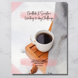 Puede incluir: Un desafío de escritura de gratitud y escritura de 30 días con una cita del Salmo 119:105. La imagen presenta una taza de café sobre una mesa de madera con una manta gris.