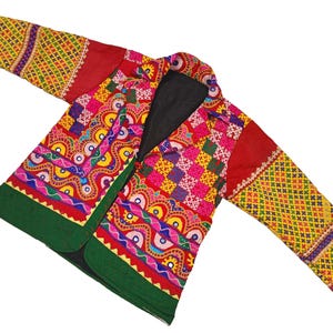 May include: A colourful, embroidered jacket with a green trim and a black lining. The jacket is made of patchwork fabric with a variety of geometric and floral patterns.