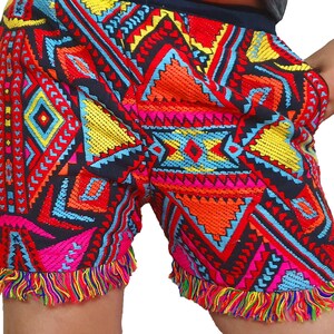 May include: Embroidered shorts with a vibrant geometric pattern in red, orange, yellow, blue, and pink. The shorts have a black background and a fringed hemline. The shorts are a colorful and eye-catching piece of clothing.