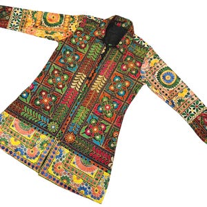 May include: A long, open-front coat with detailed embroidery. The coat displays a patchwork design with floral and geometric patterns in various colours, including red, green, yellow, and blue. The sleeves are long, and the coat has a black collar.