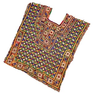 Puede incluir: Textil bordado colorido con escote cuadrado. La prenda presenta un patrón geométrico en tonos azules, verdes, amarillos y rojos, adornado con pequeños espejos reflectantes. Los bordes están ribeteados con un borde amarillo.