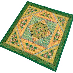 May include: A green square cushion with a colourful patchwork design featuring gold, yellow, and red accents. The cushion has a geometric pattern with intricate embroidery.