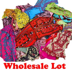 Könnte beinhalten: Eine Großhandelsmenge bunter Textilien, darunter bestickte Stoffe in Rot-, Rosa-, Blau-, Gelb- und Grüntönen. Die Textilien weisen komplizierte Muster und Designs auf. Der Text "Wholesale Lot" ist rot am unteren Bildrand zu sehen.