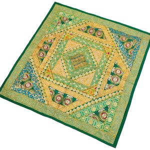 May include: A green square cushion with a colourful patchwork design featuring gold, green, and blue fabrics. The cushion is decorated with intricate embroidery and sequins.