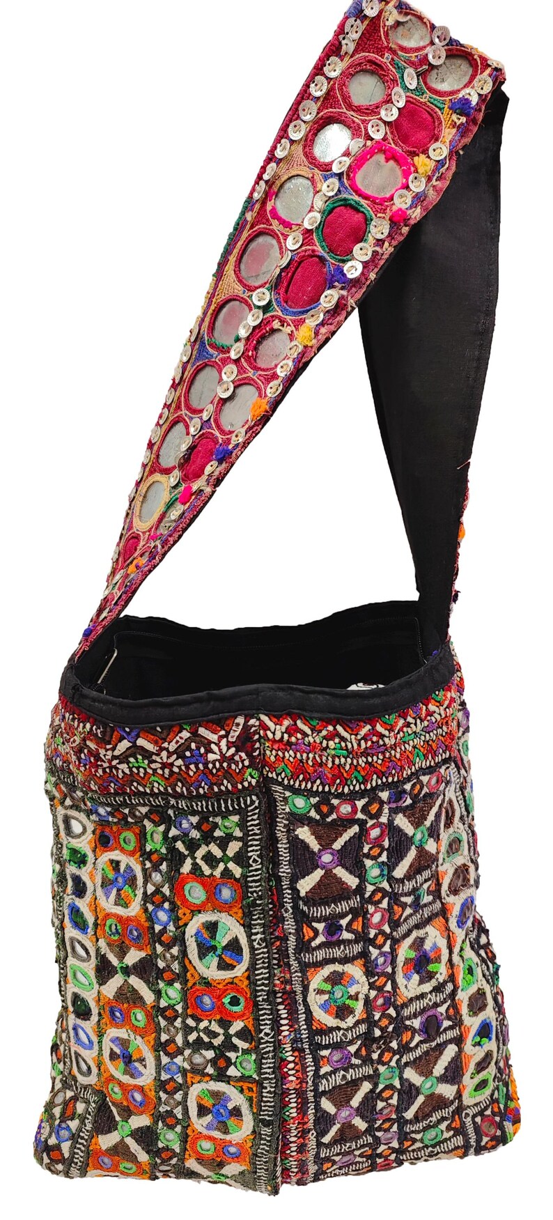 K&ouml;nnte beinhalten: Eine bestickte Umh&auml;ngetasche mit schwarzem Riemen. Die Tasche zeigt komplizierte Muster in Rot, Orange, Gr&uuml;n und Blau, mit kleinen Spiegeln und dekorativen N&auml;hten. Der Riemen ist mit Spiegeln und rotem Stoff verziert.