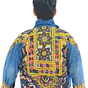 Puede incluir: Chaqueta vaquera azul con bordados vibrantes. La parte trasera de la chaqueta presenta un gran diseño colorido con patrones florales y geométricos en amarillo, rosa, azul y verde. Las mangas y el cuello son de mezclilla azul clásica.