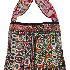 K&ouml;nnte beinhalten: Bunte, bestickte Tragetasche mit Schulterriemen. Die Tasche weist aufwendige Perlenarbeiten in verschiedenen Farben auf, darunter Rot, Blau, Gr&uuml;n und Orange. Der Riemen ist mit kleinen, runden Spiegeln verziert. Das Design der Tasche ist geometrisch und ethnisch.