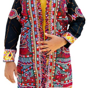 May include: A long, colourful jacket with intricate embroidery in red, green, and blue. The jacket features black sleeves with decorative patterns and a fringed trim. The garment has a yellow lining and is adorned with various embellishments.