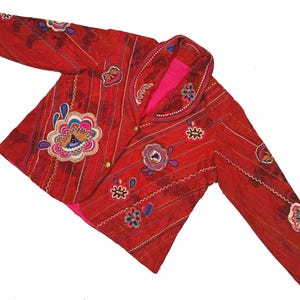 May include: A red quilted jacket with a large collar and intricate embroidered floral designs in shades of pink, blue, and brown.