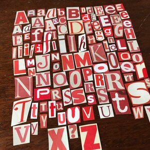 Puede incluir: Una colecci&oacute;n de letras del alfabeto de papel rojo y blanco, recortadas de revistas o peri&oacute;dicos. Las letras est&aacute;n dispuestas en un orden aleatorio, con algunas letras que aparecen varias veces.