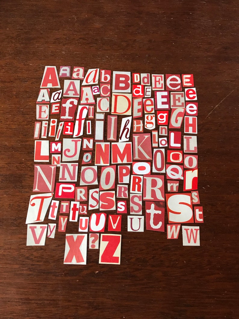 Puede incluir: Una colecci&oacute;n de letras del alfabeto de papel rojo y blanco, recortadas de revistas o peri&oacute;dicos, dispuestas en orden alfab&eacute;tico sobre una superficie de madera marr&oacute;n.
