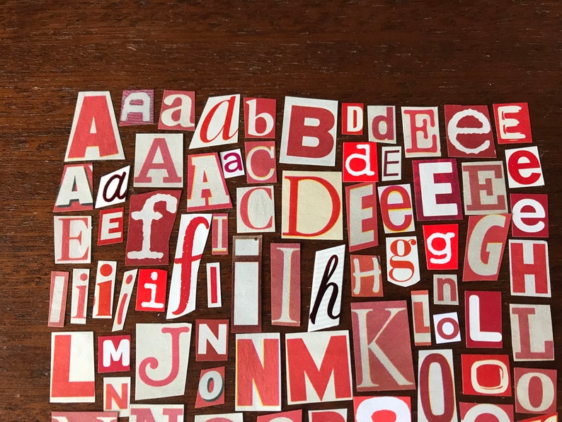 Puede incluir: Una colecci&oacute;n de letras rojas, blancas y crema cortadas de papel y dispuestas en un patr&oacute;n aleatorio sobre una superficie de madera marr&oacute;n. Las letras incluyen A, B, C, D, E, F, G, H, I, J, K, L, M, N, O.