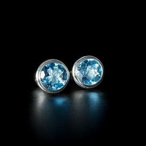 Peut inclure: Une paire de boucles d'oreilles en argent avec des pierres rondes en topaze bleue.