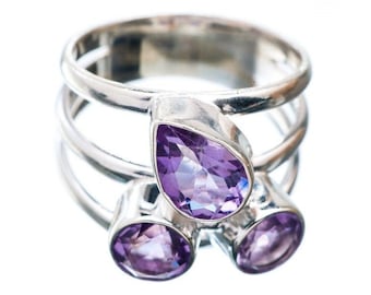 May include: A silver ring with three amethyst stones. The stones are pear-shaped and set in a silver band. The ring is a delicate and elegant piece of jewelry.