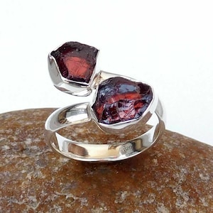 May include: A sterling silver ring with two red garnet stones. The ring is a wrap-around style and has a 925 stamp on the inside.
