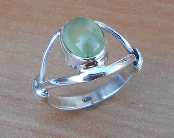 May include: A silver ring with a green oval gemstone set in a delicate, open-work design. The ring is marked "925" on the inside band.
