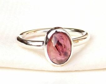May include: A silver ring with a pink oval gemstone set in a bezel setting.